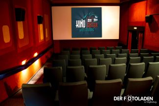 Kinosaal Camera mit Blick auf Sitzreihen und Leinwand